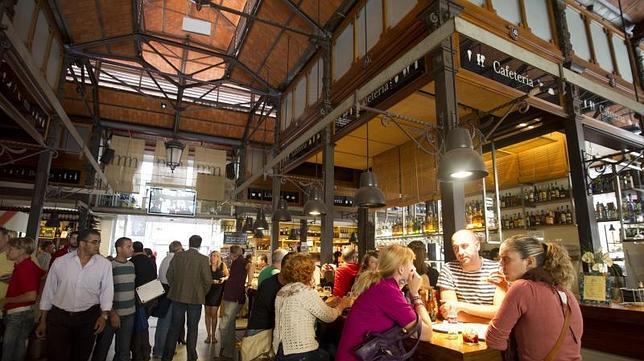 Los clientes se toman una caña en uno de los bares que se han instalado en el mercado de San Miguel