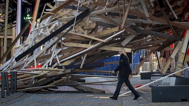 Una mujer pasa junto a parte de la estructura caída de la obra gigante 'The Passenger', del artista belga Arne Quinze, en Mons (Bélgica)