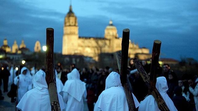 La Hermandad del Santísimo Cristo del Amor y de la Paz, a su paso por el puente romano, con el conjunto monumental de Salamanca al fondo