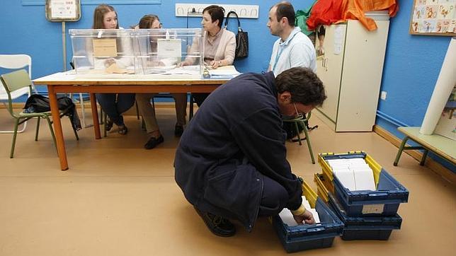 Un funcionario de correos entrega los votos por correo en un colegio electoral de Madrid