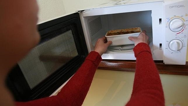 Una mujer calienta la comida sobrante